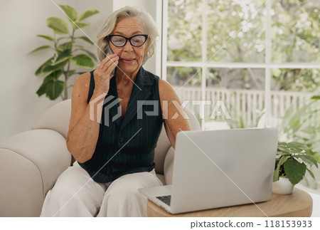 Senior Woman Uses Laptop at Home Surrounded by Plants, Embracing Modern Digital Living Senior Woman Uses Laptop at Home Surrounded by Plants, Embracing Modern Digital Living 118153933