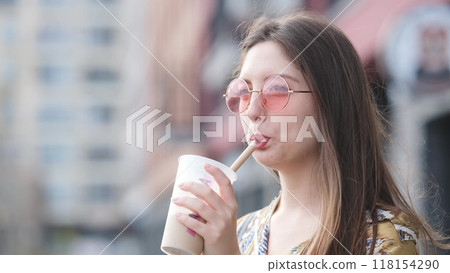 Pensive happy woman sipping a milkshake in the street Pensive happy woman sipping a milkshake in the street 118154290
