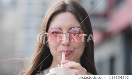 Pensive happy woman sipping a milkshake in the street Pensive happy woman sipping a milkshake in the street 118154292