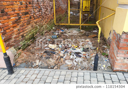 The walls of a brick house. Garbage is lying between the houses. 118154304
