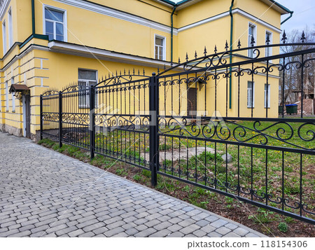 Black beautiful new cast iron openwork fence on a cloudy autumn day 118154306