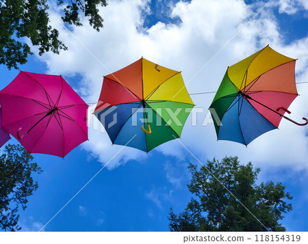 Under the blue sky, under the colorful umbrellas hanging over the alley of the city park Under the blue sky, under the colorful umbrellas hanging over the alley of the city park 118154319