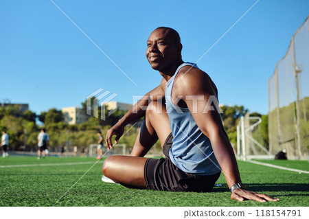 Athletic man sitting on grassy sports football field 118154791
