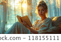 A woman reading a book by a window with soft, natural morning light streaming in 118155111