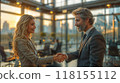 A man and woman shaking hands in a bright modern office setting, sealing a business deal 118155112