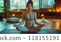 A young woman practicing yoga in a peaceful, minimalist home setting with soft lighting 118155191