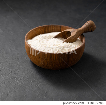 Wheat or oat flour in a wooden bowl with scoop on a dark background. Organic baking ingredients. Concept of homemade and healthy food. Wheat or oat flour in a wooden bowl with scoop on a dark background. Organic baking ingredients. Concept of homemade and healthy food. 118155786