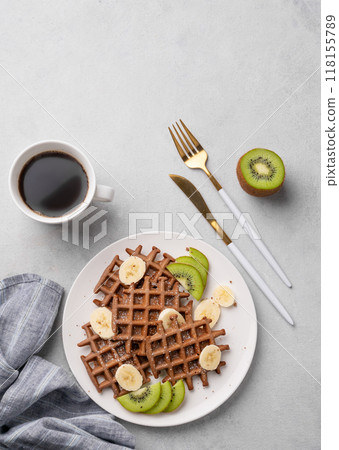 Belgian vegetarian waffles with kiwi, blueberries and banana slices on a white plate  118155789