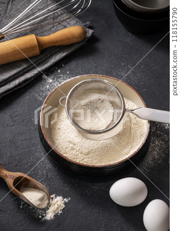 Flour, eggs and rolling pin on a dark background close up. Organic baking ingredients. Flour, eggs and rolling pin on a dark background close up. Organic baking ingredients. 118155790