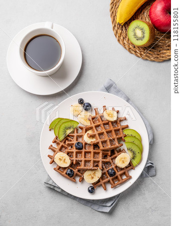 A freshly prepared vegan waffles with kiwi, blueberries and banana slices on a white plate A freshly prepared vegan waffles with kiwi, blueberries and banana slices on a white plate 118155801