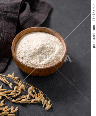 Oat  flour and dry branch on a dark  background with napkin. Organic baking ingredients. 118155802