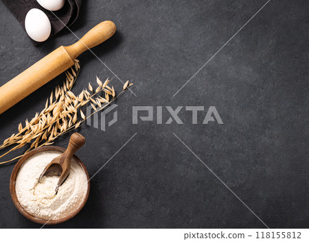 Oatmeal, eggs and rolling pin on a dark background. Organic baking ingredients. Oatmeal, eggs and rolling pin on a dark background. Organic baking ingredients. 118155812