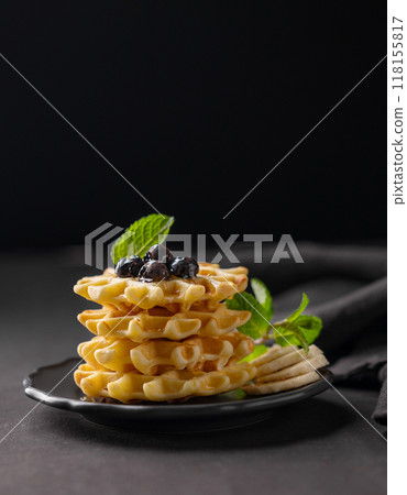 A stack of freshly prepared waffles with kiwi, banana slices and mint, drizzled with honey syrup 118155817