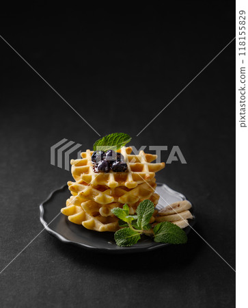 A stack of belgian waffles with kiwi, banana slices and mint, drizzled with honey syrup  118155829