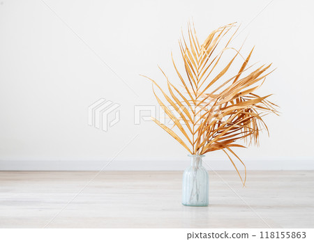 Stylish modern dry palm leaves in glass vase on a wooden light floor in room in Scandinavian style.  118155863
