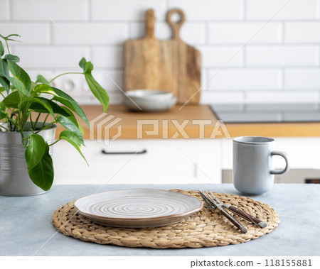 Wooden blue table top with flower pot, plate and cup for breakfast against blurred white kitchen 118155881