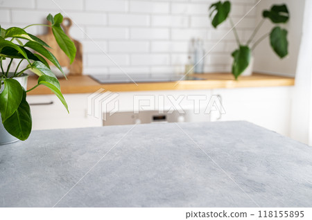 Wooden blue table top with flower pot against blurred white kitchen with cutting board 118155895