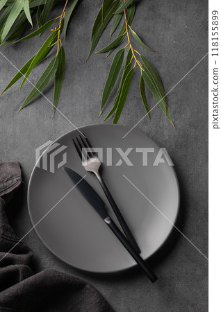 Festive table setting with empty gray plate and black cutlery for holiday with eucalyptus Festive table setting with empty gray plate and black cutlery for holiday with eucalyptus 118155899