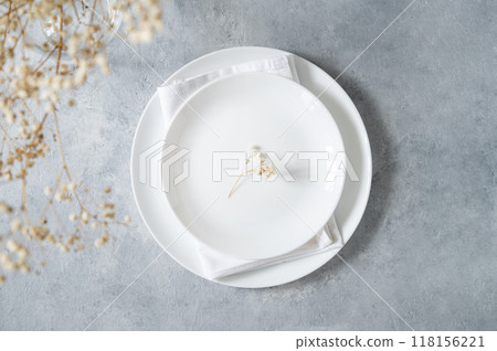 Table setting in a minimalist style with white plate and a bouquet of gypsophila Table setting in a minimalist style with white plate and a bouquet of gypsophila 118156221