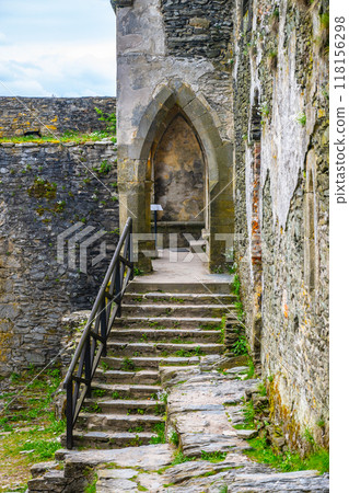 Ancient stone stairs lead upward through the walls of Bezdez Castle, surrounded by weathered stones and vibrant greenery, evoking a sense of history and mystery in Czechia. 118156298