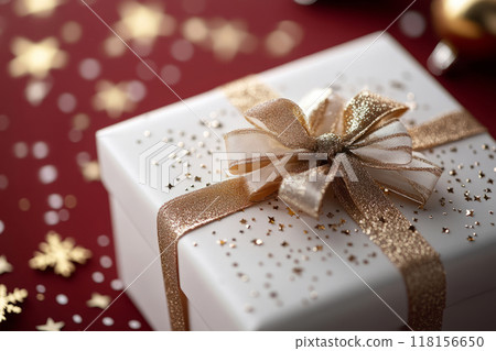 Christmas gift with a gold ribbon and bow on a red background, surrounded by festive decorations and sparkling stars 118156650