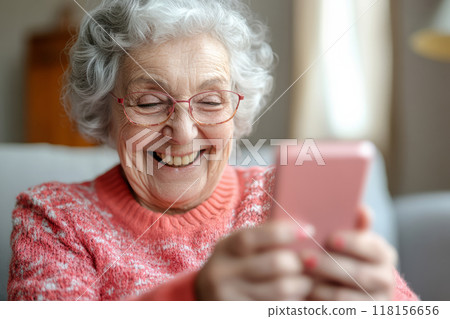 Elderly woman smiles while using a smartphone 118156656