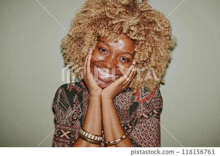 Beautiful woman touching her face and smiling sincerely while posing Beautiful woman touching her face and smiling sincerely while posing 118156763