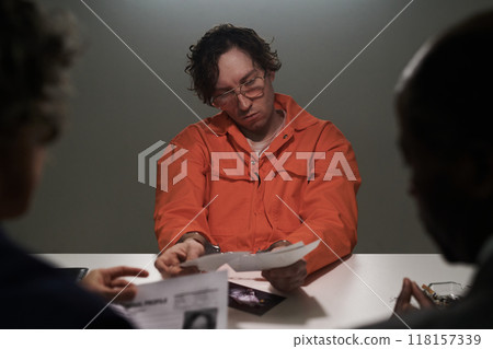 Reviewing Documents in Orange Prison Uniform During Interview 118157339