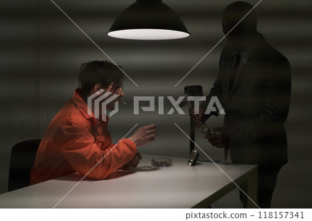 Officer Interrogating Suspect Under Dim Light Officer Interrogating Suspect Under Dim Light 118157341