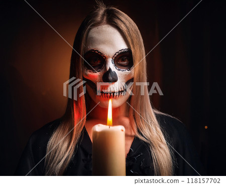 Woman in Skull and Bone Mask, Candlelight Illumination, Day of the Dead, and Halloween Theme 118157702
