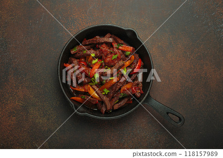 Lomo saltado, beef and red pepper stir fry cooking in cast iron pan, traditional Peruvian dish 118157989