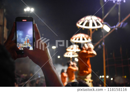 View of hands with phone taking photos at Aarti ceremony on bank of Ganges river 118158116