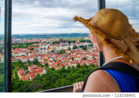 Lady tourist looking at the cityscape from the Prague Castle tower window 118158401