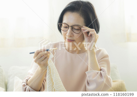 Middle-aged woman knitting in the living room 118160199