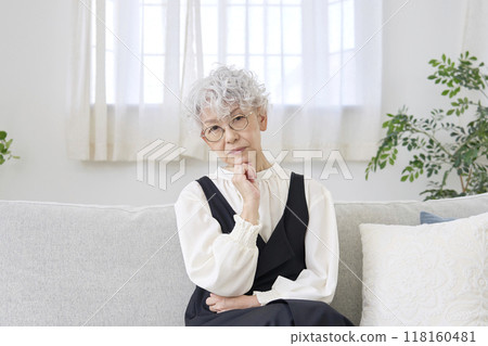 Thinking senior woman living room looking at camera Thinking senior woman living room looking at camera 118160481