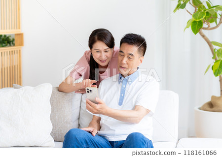 一對老夫婦在客廳裡看智能手機 118161066
