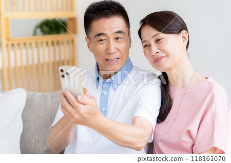 Senior couple looking at a smartphone in the living room 118161070