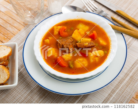 Image of appetizing tender stewed veal with sauce with potatoes and vegetables. Spanish appetizer - patatas estofadas con carne Image of appetizing tender stewed veal with sauce with potatoes and vegetables. Spanish appetizer - patatas estofadas con carne 118162582