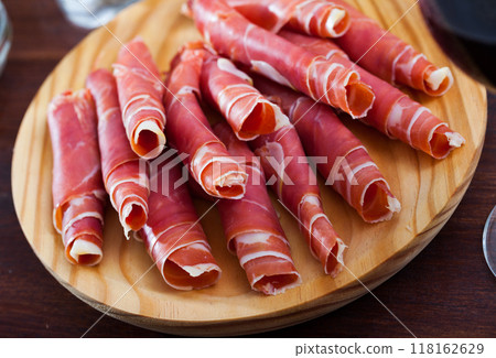 Spanish dry cured jamon on wooden plate 118162629