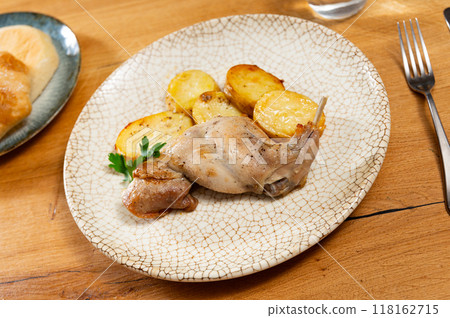 Lunch is served on plate - pieces of young rabbit cooked with segments of potato. Close-up Lunch is served on plate - pieces of young rabbit cooked with segments of potato. Close-up 118162715