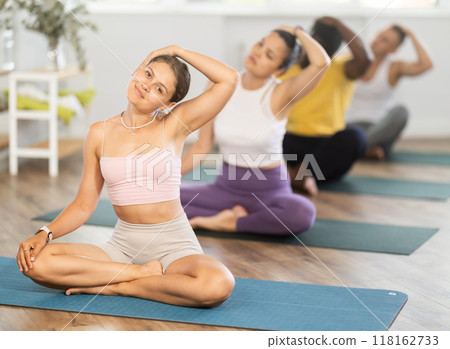 Young woman doing yoga in group in studio 118162733