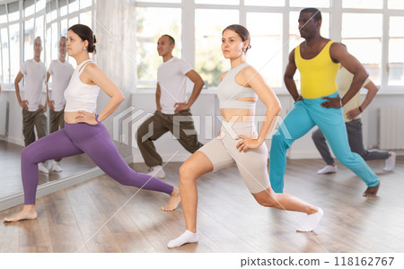 Young female instructor leading group stretching routine 118162767
