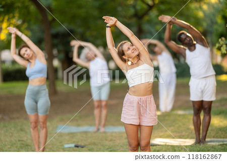 Girl doing Nitambasana at group yoga class in park 118162867