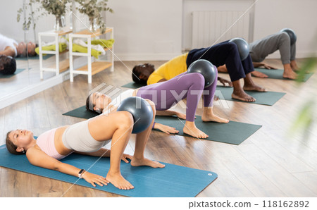 Men and woman diligently perform set of exercises with fitball during training session 118162892