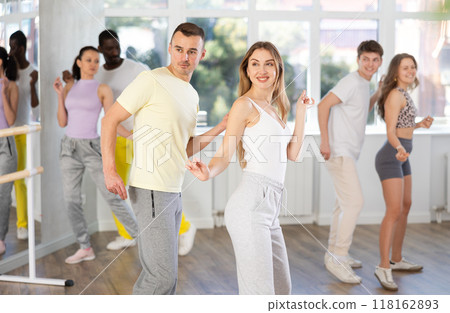 Young man and woman practicing active dance in pair in training hall Young man and woman practicing active dance in pair in training hall 118162893