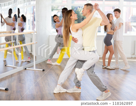 Woman in sports clothes learn to dance couples latin dance, energetic and fast tango in dance salon Woman in sports clothes learn to dance couples latin dance, energetic and fast tango in dance salon 118162897