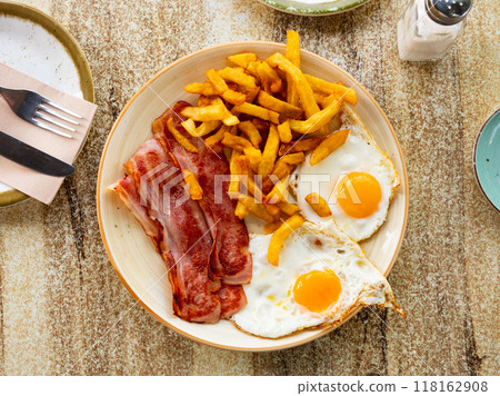 Bacon with fried potato and egg served on plate on table 118162908