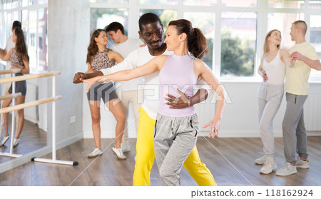 Woman with African man dancing waltz in couple during lesson at studio 118162924
