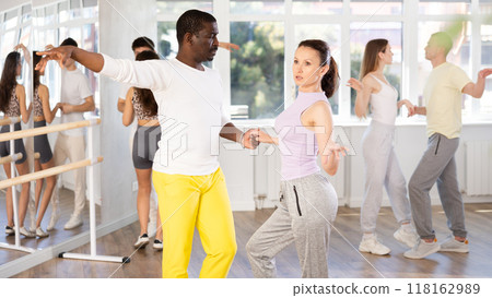 Beautiful young woman at dance salon with her african american partner dancing active boogie-woogie dance 118162989