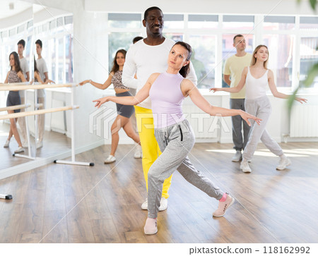 Woman performing curtsy with African American partner in pdance studio Woman performing curtsy with African American partner in pdance studio 118162992